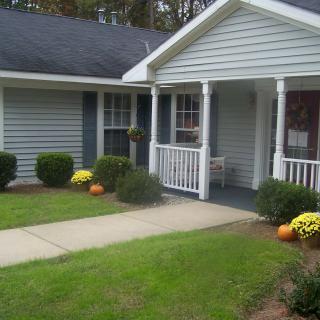 A cozy house with a front porch, surrounded by a well-maintained garden.