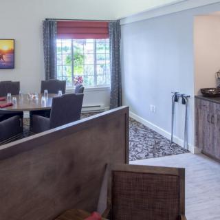 A cozy dining room featuring a table set with chairs, illuminated by natural light from a large window.