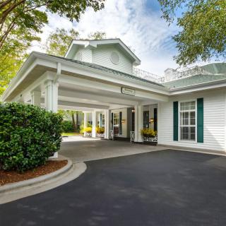 A welcoming building entrance with a driveway surrounded by trees.