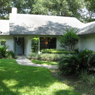A cozy residential house surrounded by lush greenery and well-maintained landscaping.