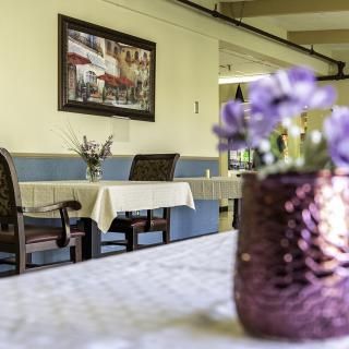 A cozy restaurant interior with neatly set tables and a vibrant floral centerpiece.