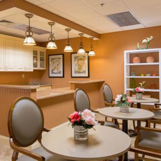 A cozy dining area with elegant decor and lighting, featuring tables adorned with flowers.
