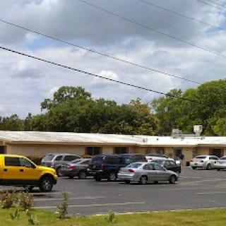 A view of a parking lot in front of a low-rise commercial building under a partly cloudy sky.