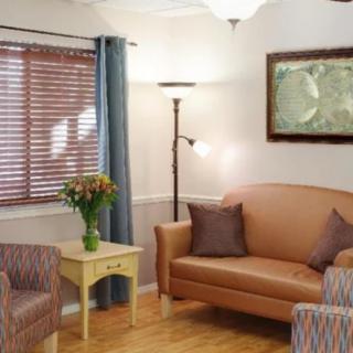 A cozy living room with a sofa, armchairs, and a vase of flowers on a side table.