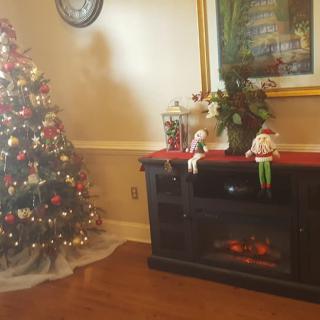 A cozy living room with a decorated Christmas tree and fireplace adorned for the holiday season.