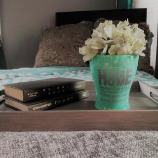 A cozy bedroom setup with a decorative tray holding books and a flower arrangement.