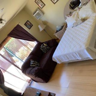 A cozy bedroom with a bed, couch, and large window with curtains.