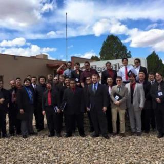 A group of people posing for a photo outdoors, dressed in formal attire.