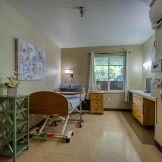 A clean and well-organized hospital room with a single bed and window.
