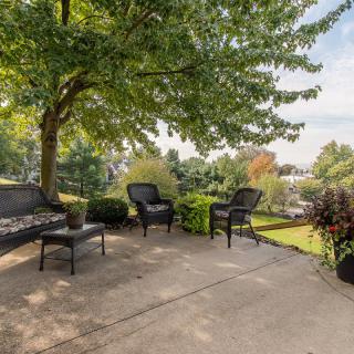A serene patio with comfortable seating surrounded by lush greenery.