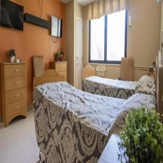 A serene hospital room featuring two patient beds with a warm color scheme and ample natural light.