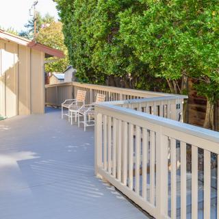 A spacious outdoor deck with chairs, surrounded by lush trees.