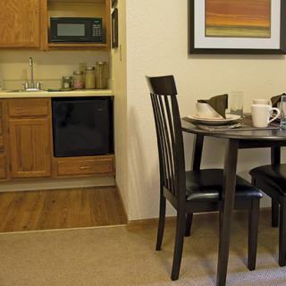 A cozy kitchen with a small dining area including a round table and chairs, adjacent to kitchen cabinets and appliances.