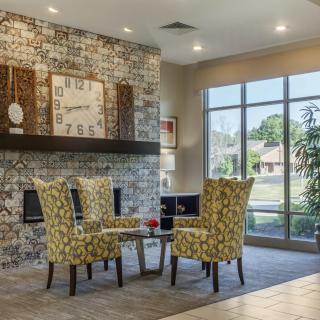 A modern living room with patterned chairs, a central table, and a large window letting in natural light.