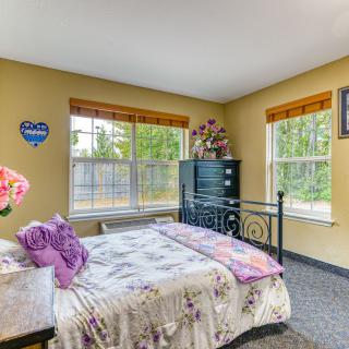 A cozy bedroom with floral bedding and ample natural light from large windows.