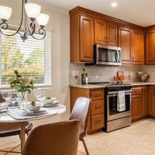 A beautifully designed kitchen featuring elegant wood cabinets and a cozy dining area, illuminated by natural light.