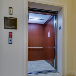 An open elevator with wooden interior walls and illuminated ceiling.