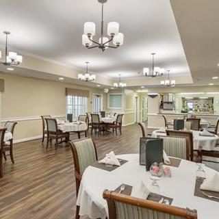 An elegantly decorated dining area with neatly arranged tables and chairs, illuminated by chandeliers.