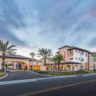 Modern residential building with palm trees under a cloudy sky.