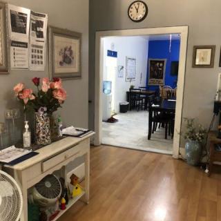 A cozy living room area with wooden flooring, featuring a decorative console table with flowers and artwork on the walls.