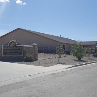 A spacious building with a welcoming sign and landscaped surroundings, under a clear blue sky.