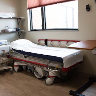 A view of a hospital room featuring an empty patient bed and medical equipment.