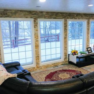 A cozy living room with large windows overlooking a snowy landscape.