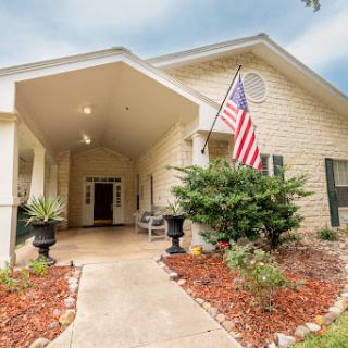 Inviting entrance to a charming home with beautiful landscaping and an American flag.