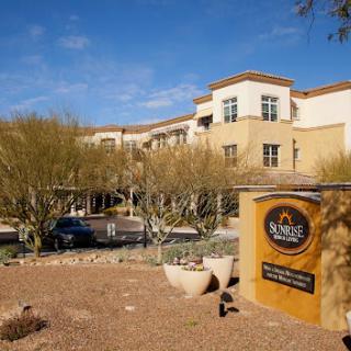 A view of a hotel surrounded by desert landscaping, featuring a prominent sign.