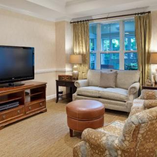 Cozy living room with a television, sofa, armchair, and ottoman.