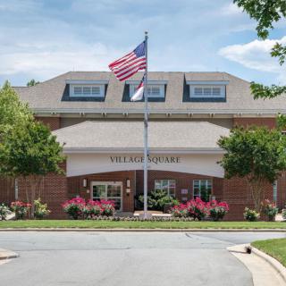 A brick building with an American flag in front, surrounded by trees and landscaping.
