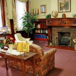 A cozy vintage living room with a fireplace, bookshelf, and classic furniture.