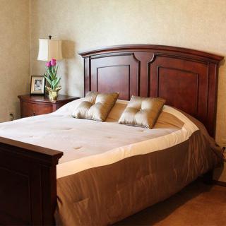 A cozy bedroom with a wooden headboard, plush pillows, and bedside tables with lamps.