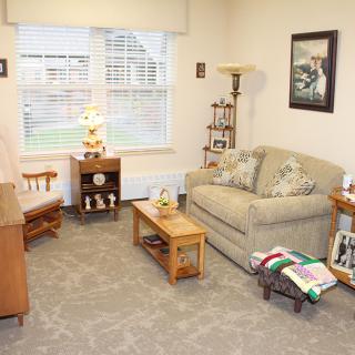 A cozy living room with a sofa, armchair, and coffee table, decorated with various items.
