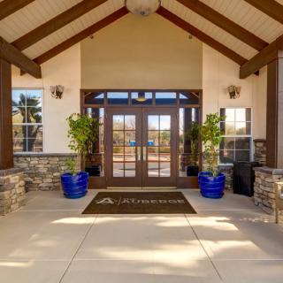 A welcoming building entrance with large glass doors and decorative potted plants.