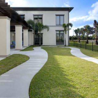A modern house with a well-maintained lawn and winding concrete pathways.
