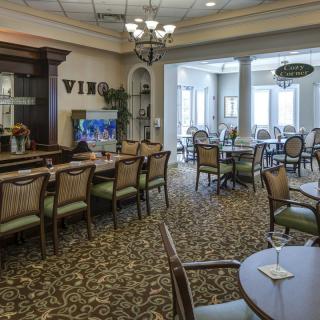 An elegantly designed dining area with multiple tables and chairs, featuring warm lighting and classic decor.
