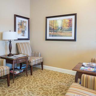 A cozy waiting room with striped chairs, framed artwork, and a decorative carpet.