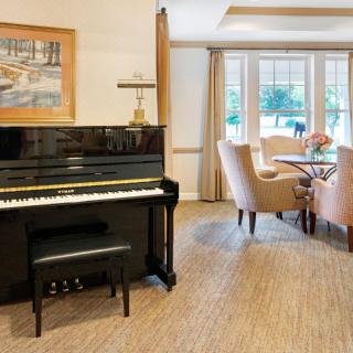 A cozy living and dining area featuring a piano and a large window.