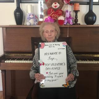 A joyful elderly person celebrating a special occasion with a festive sign at the piano.