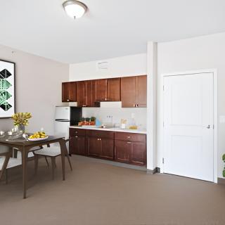 A modern kitchen with wooden cabinets, dining table, and chairs.