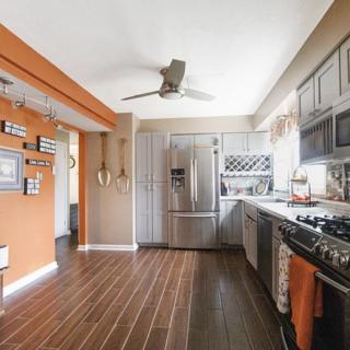 A modern kitchen with orange accents and stainless steel appliances.