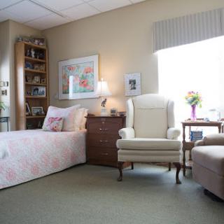 A cozy and well-decorated bedroom featuring a bed, an armchair, a bookshelf, and a warm atmosphere.