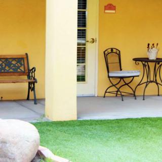 A cozy patio with a bench, table, and chairs set against a yellow wall.