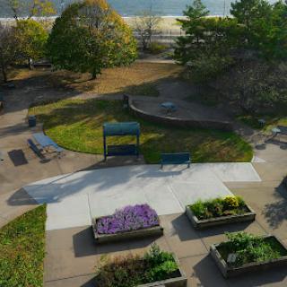 A serene view of a park with flower beds and seating areas, surrounded by trees.
