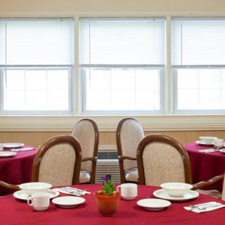 An elegantly set dining area with red tablecloths, neatly arranged place settings, and comfortable chairs.