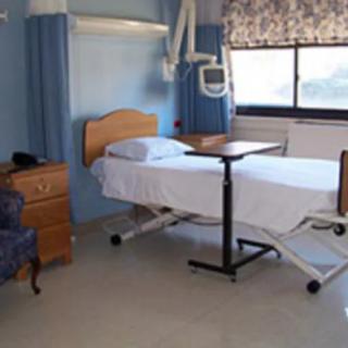 An empty hospital room with a bed and medical equipment.