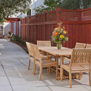 Wooden patio furniture set with a floral centerpiece in an outdoor garden setting.