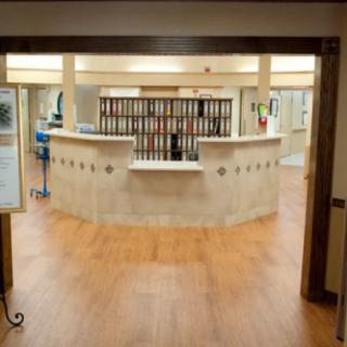 A spacious reception area featuring a central desk and warm wooden flooring.