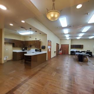 A spacious interior featuring a kitchen area and office workspace with a warm wooden floor.